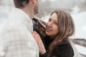 A couple sharing an intimate winter moment wrapped in a white scarf.