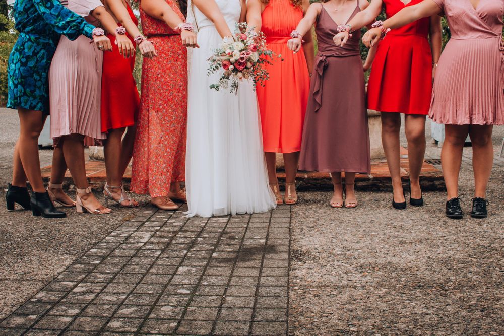 Wedding party showing colorful bridesmaid dresses and shoes lined up on cobblestone ground.