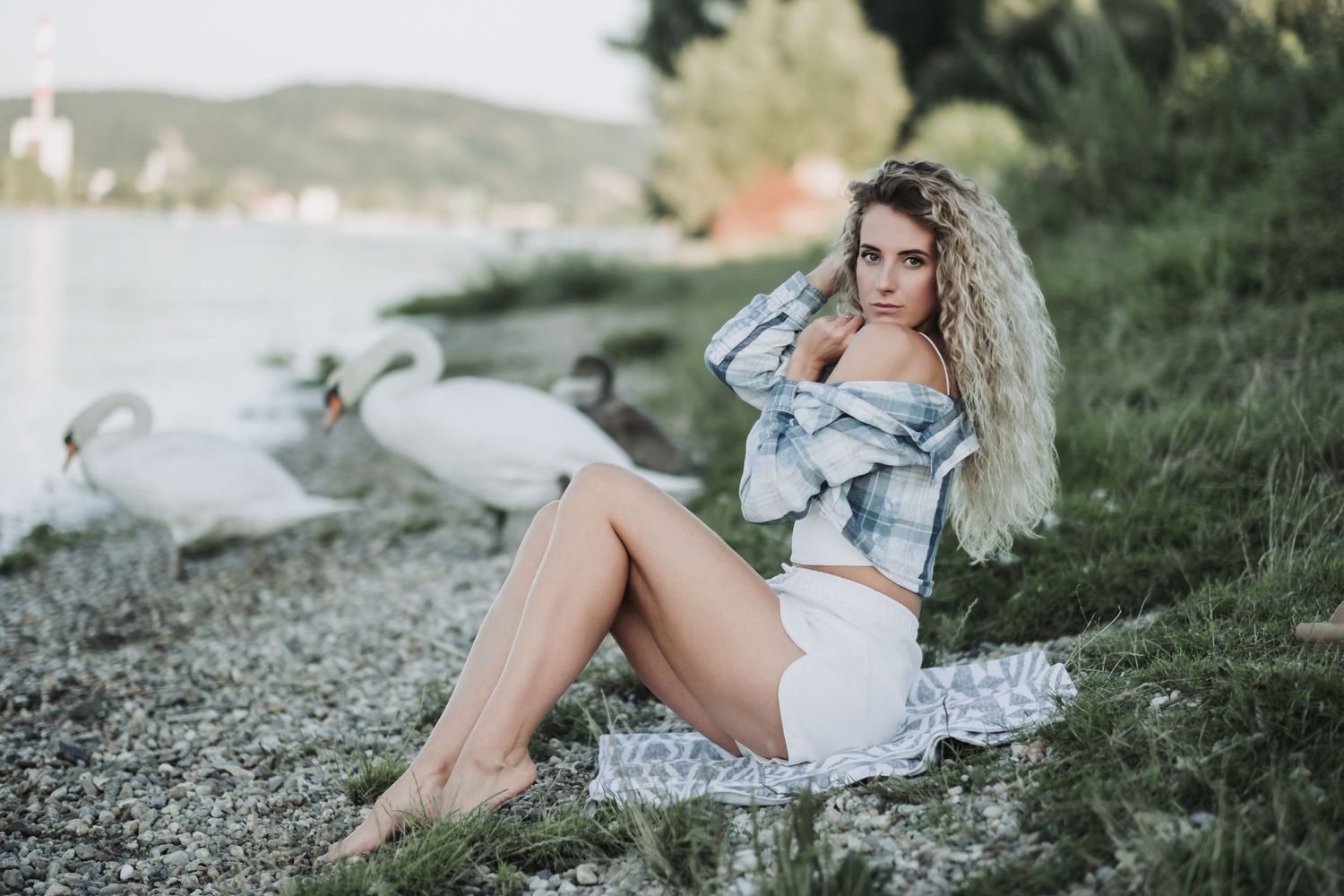 Outdoor portrait by a lake with swans in the background during sunset.