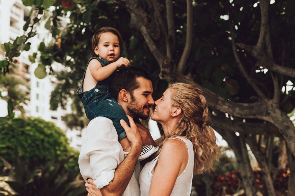 Family sharing a joyful moment together under a large tree.