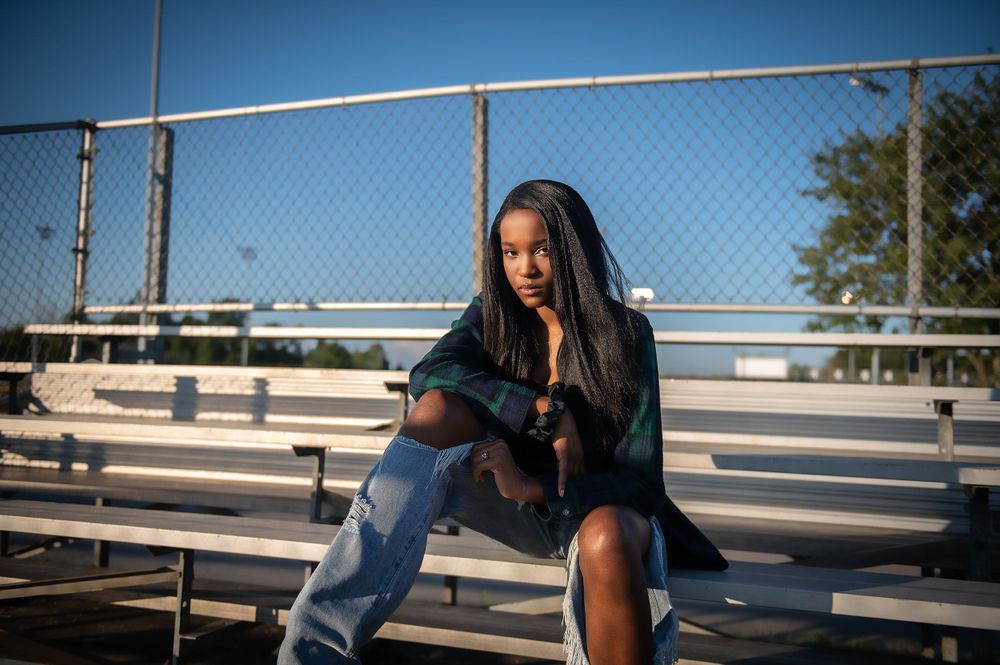 Urban photography session featuring chain link fence and blue sky backdrop.