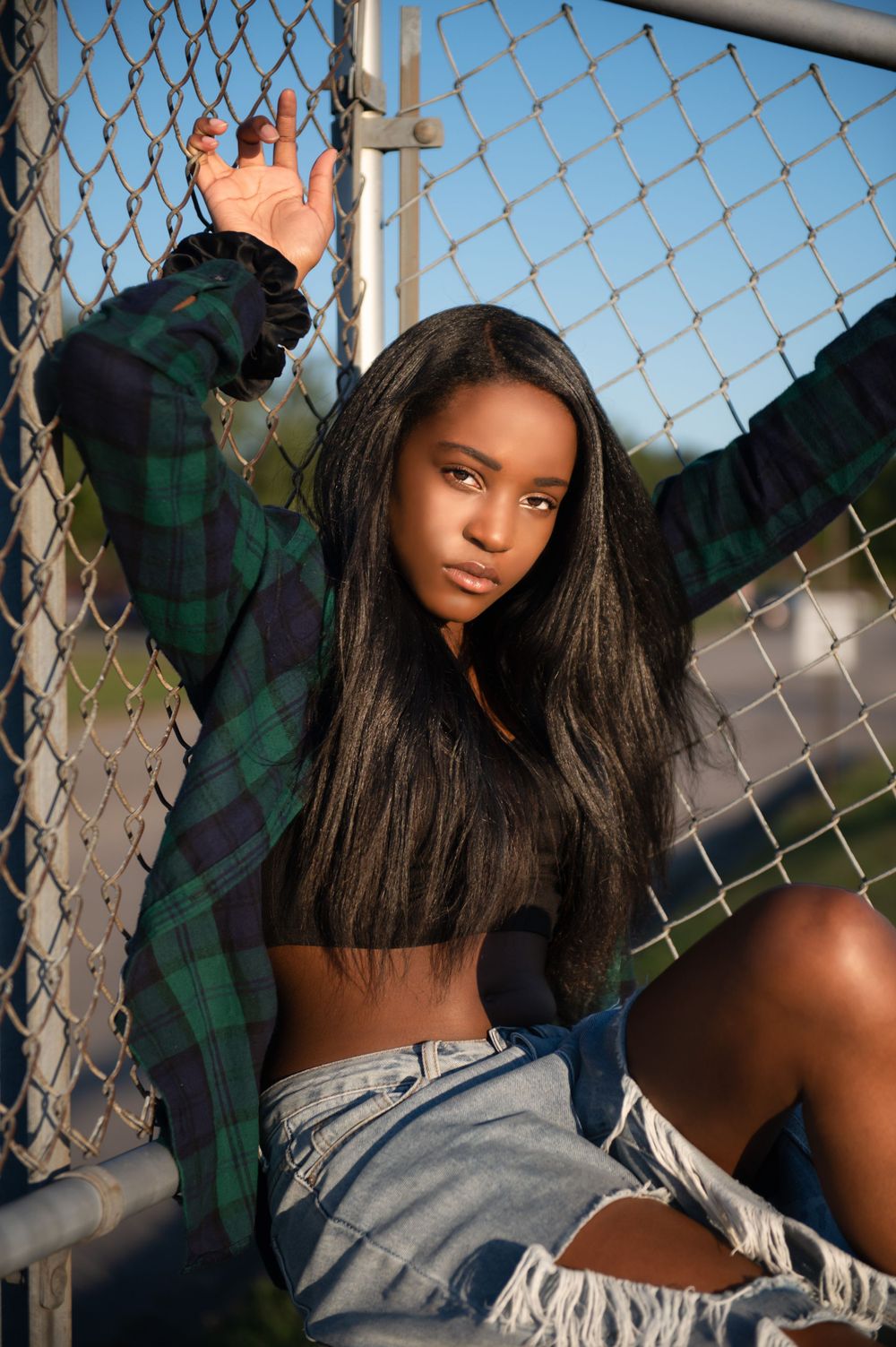 Artistic portrait series against chain link fence with green plaid shirt and natural lighting.
