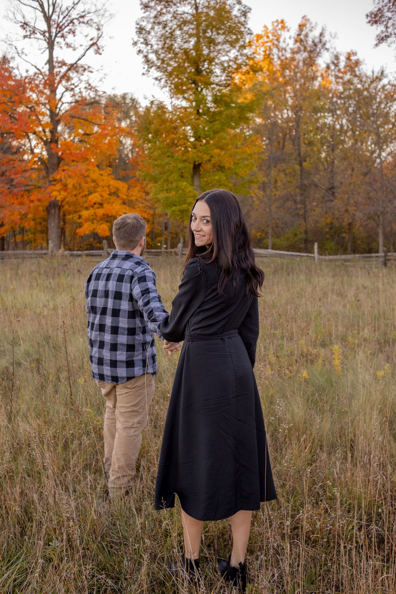 man leading girl  into field,  while girl looks back