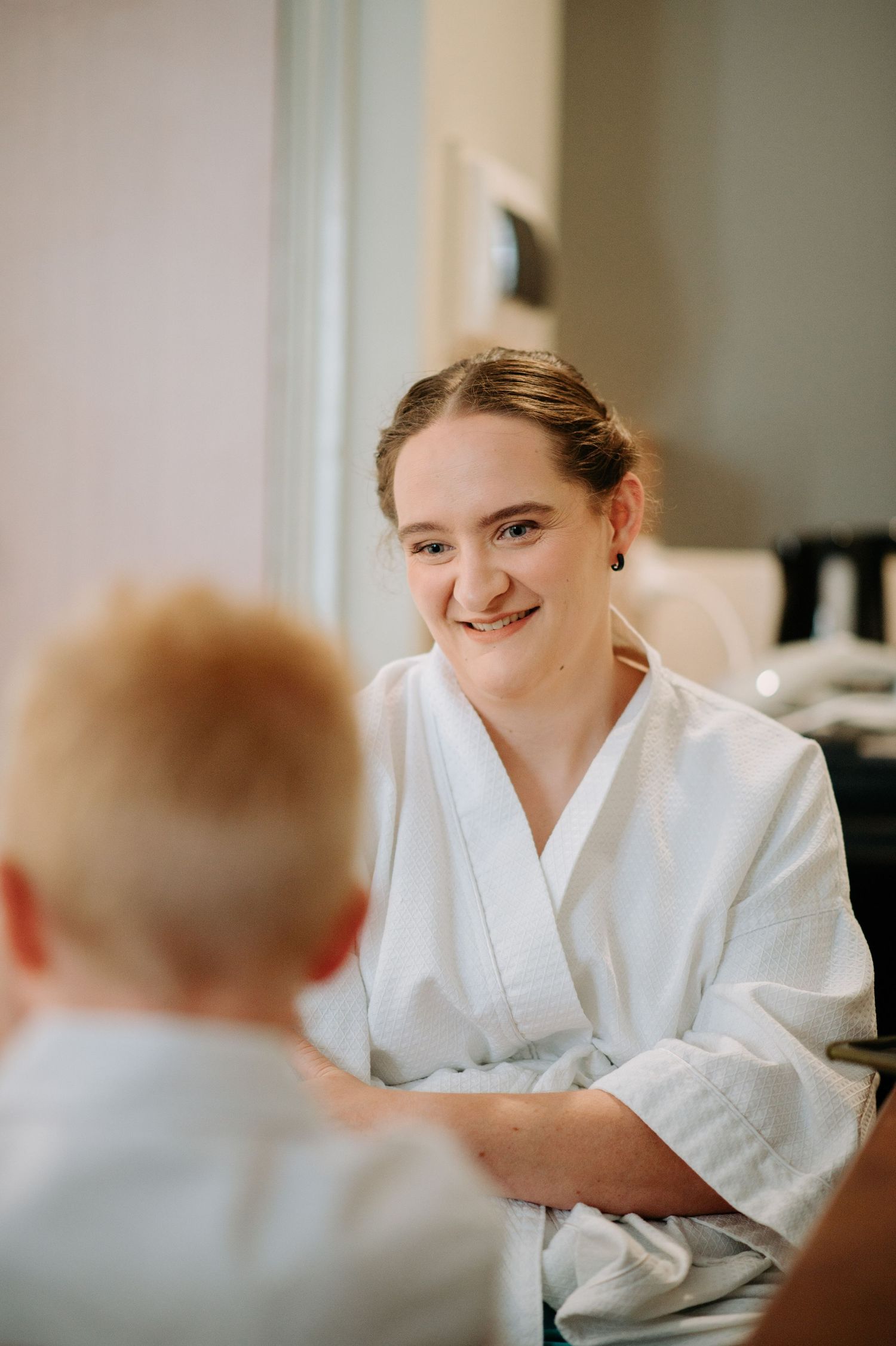 A person in a white robe smiles while getting ready in the morning.