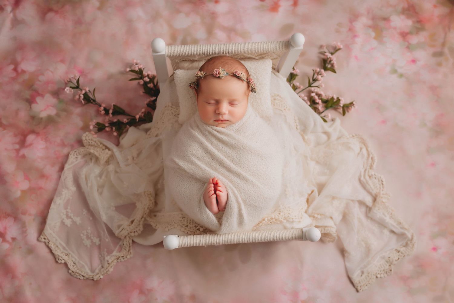 Tampa Newborn Photographer- baby in bed with rose headband