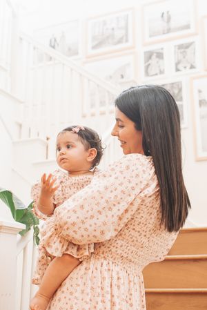 Series of playful interactions near white staircase with framed photos in background.