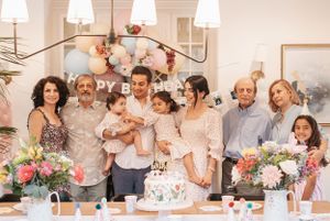 Extended family gathered around a birthday cake for a celebration photo.