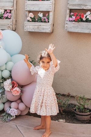 Birthday party decor with pastel balloons and wooden planter boxes filled with flowers.