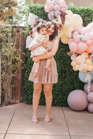 Beautiful outdoor birthday party setup with pink balloon arch and floral decorations on a patio.