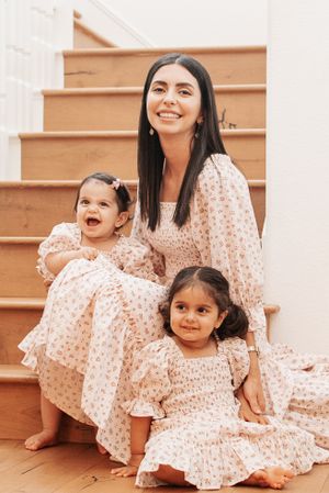 Coordinated family portrait in matching floral dresses on wooden stairs.