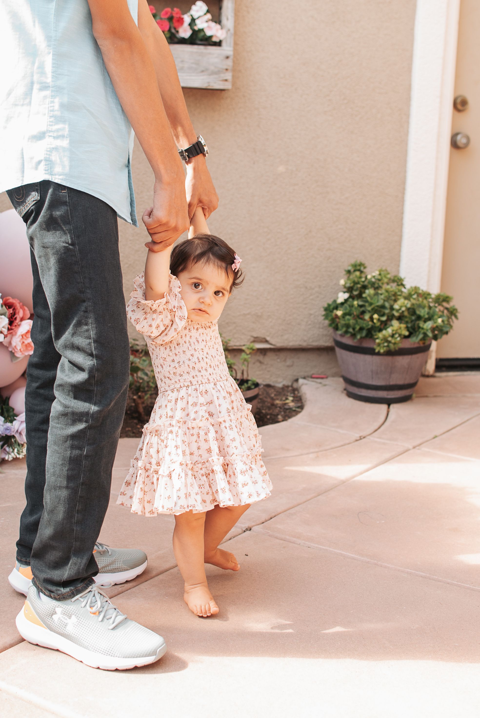 Cropped view of feet and legs on a patio with pink floral dress visible.