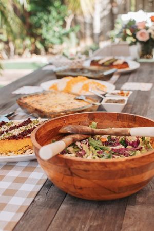 Fresh garden salad served in wooden bowls on a checkered tablecloth outdoors.