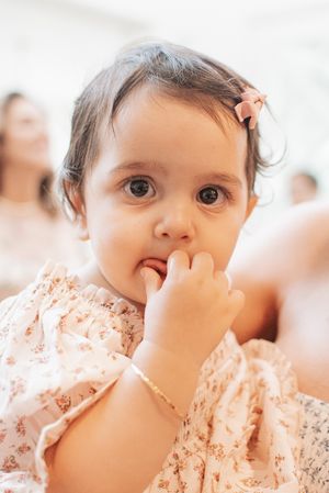 Close-up of a toddler in a floral dress with a thoughtful expression.