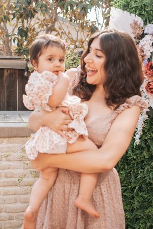 Sweet moment between two in matching blush dresses against a garden backdrop.