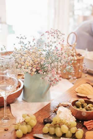 Party table setting with wine, grapes, and delicate baby's breath flowers in a vase.