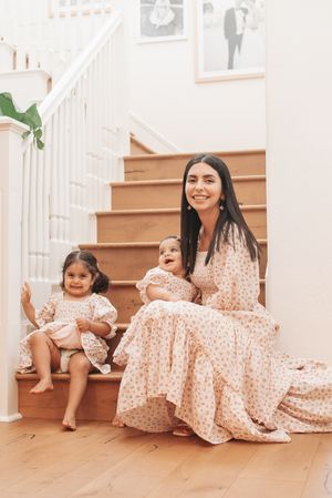 Matching outfits in polka dot dresses sitting on wooden staircase.