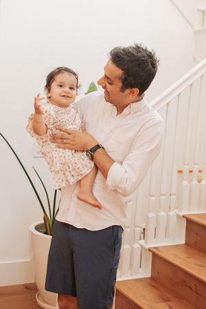 Series of gentle interactions between adult and child near white staircase.