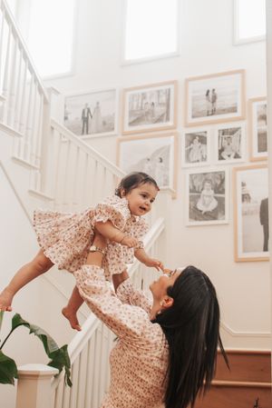 Playful sequence showing lifting and twirling moments near white staircase and photo gallery.