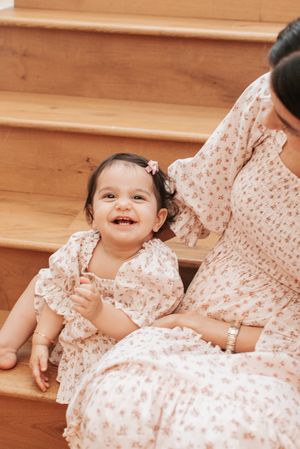 Sequence showing child in floral dress laying on wooden stairs with joyful expressions.