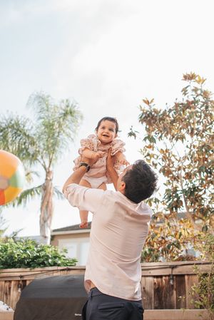 Two people share a joyful moment outdoors with balloons and palm trees in the background.