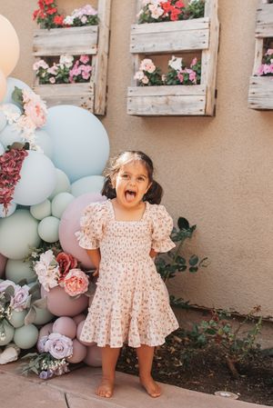 Joyful celebration moment against wall decorated with pastel balloons and roses.