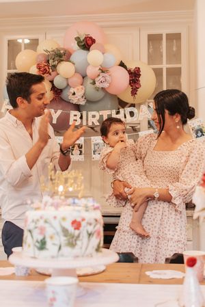 Family gathers around a beautiful floral birthday cake at a celebration.