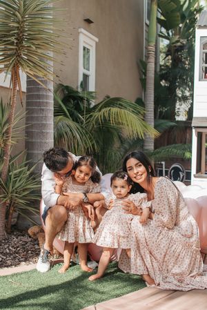 Family gathering on artificial turf with palm trees and tropical landscaping.