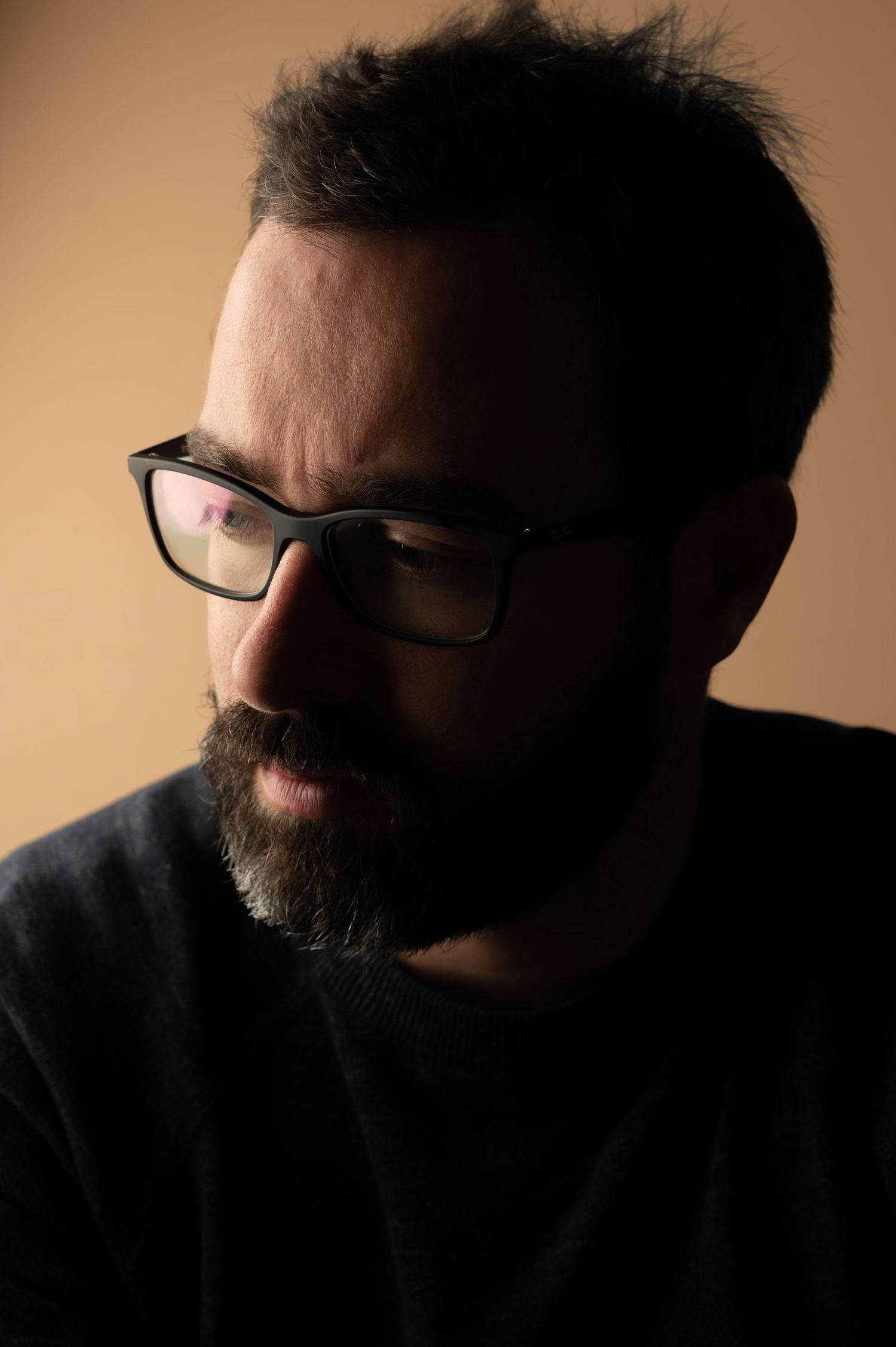 Moody portrait series with dramatic lighting against a warm background.