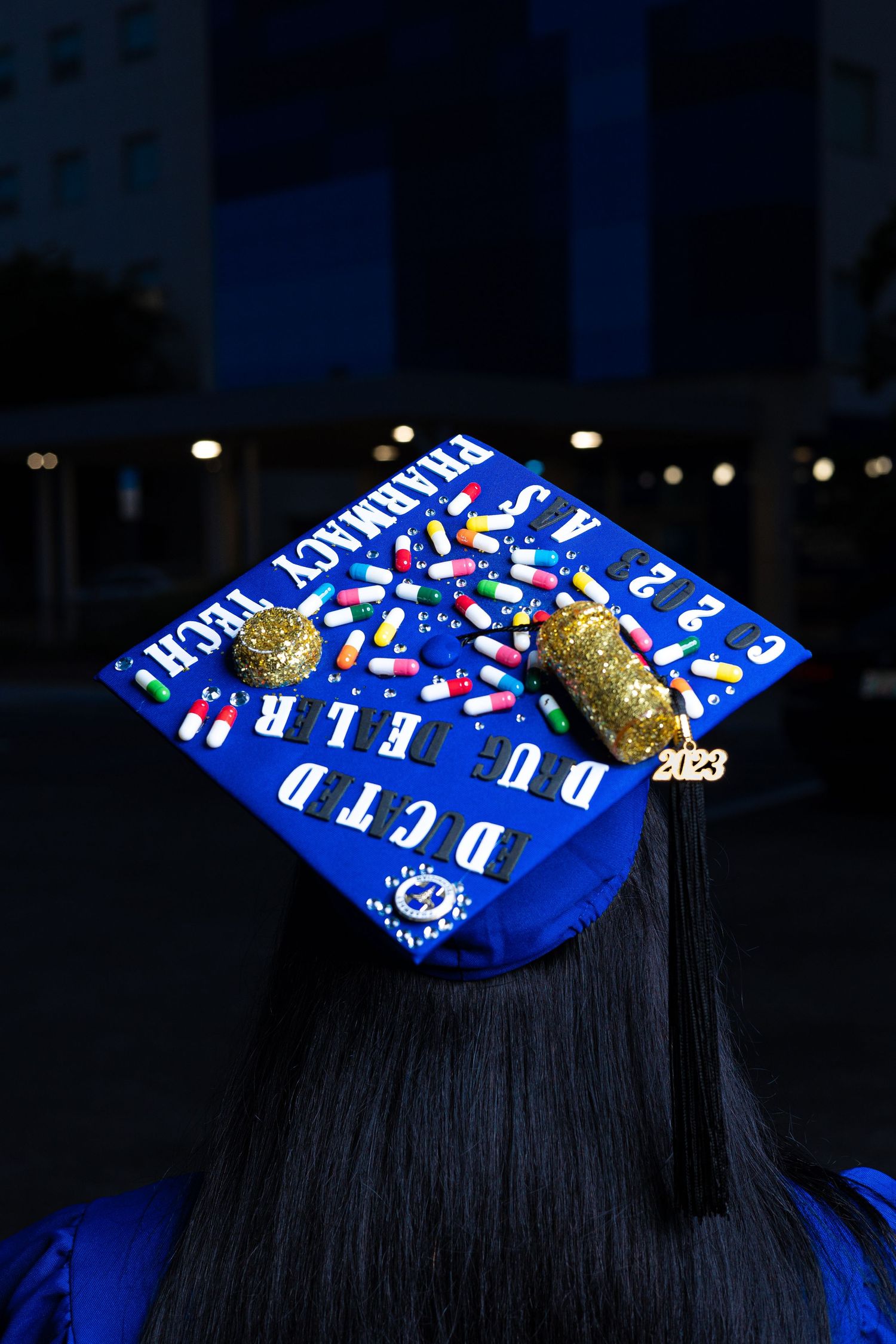 Decorated graduation cap with blue and gold design photographed at night.