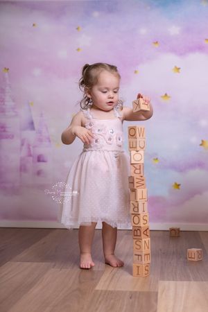 A dreamy nursery scene with stacked alphabet blocks against a purple cloudy backdrop with golden stars.