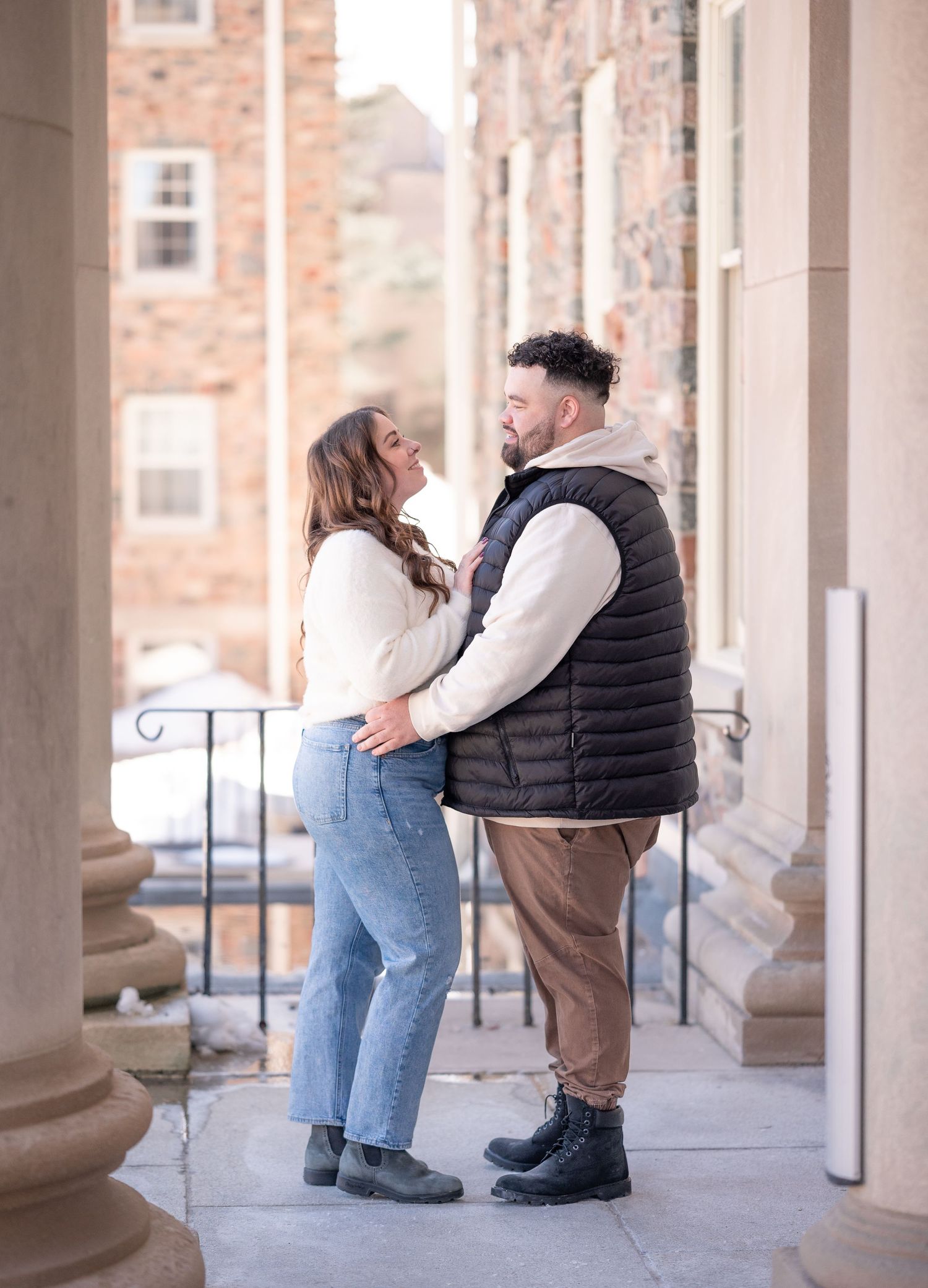Couple gazing into each other's eyes with beautiful historic buildings and pillars framing them.