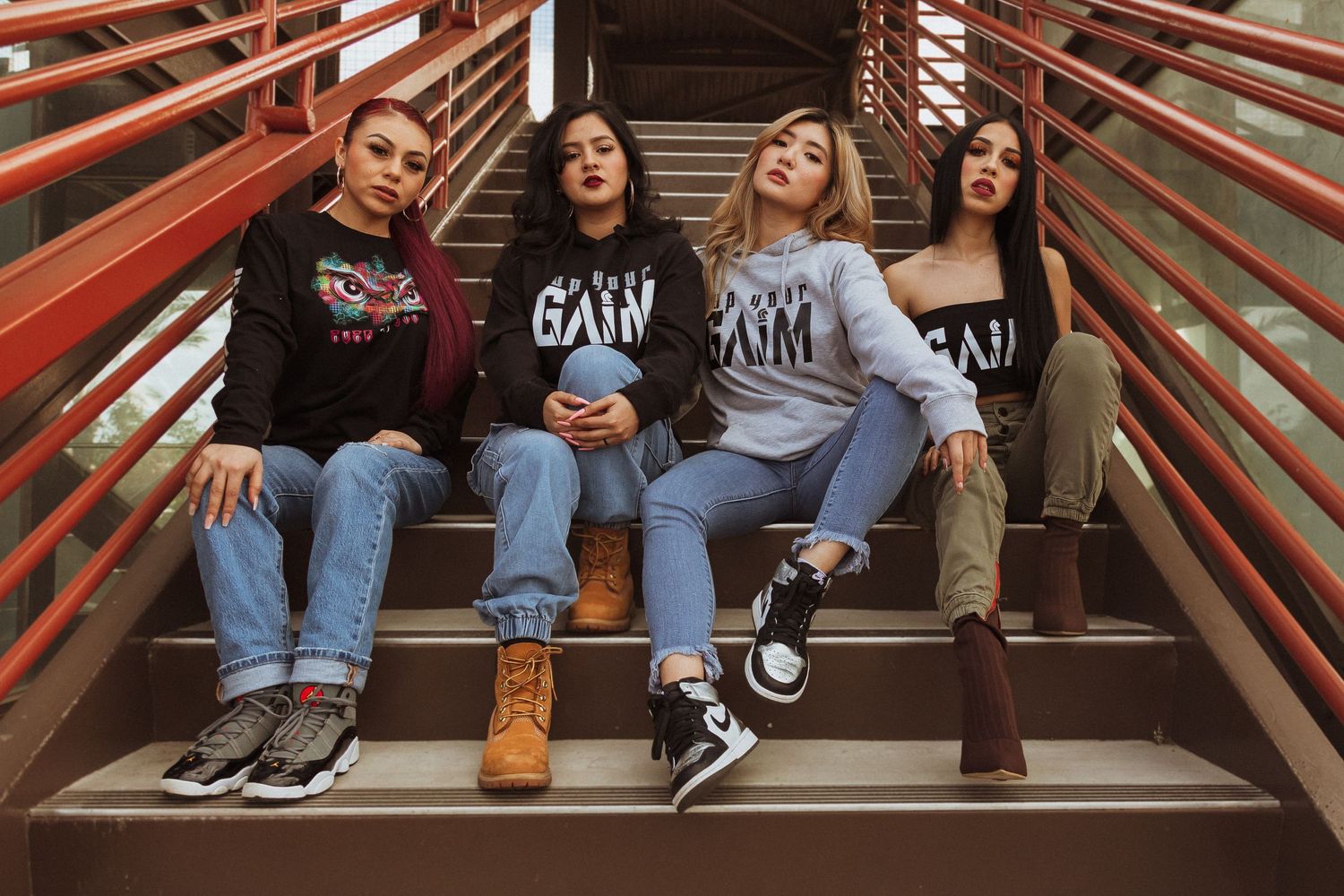 A group sits on red metal bleacher steps wearing matching graphic t-shirts.