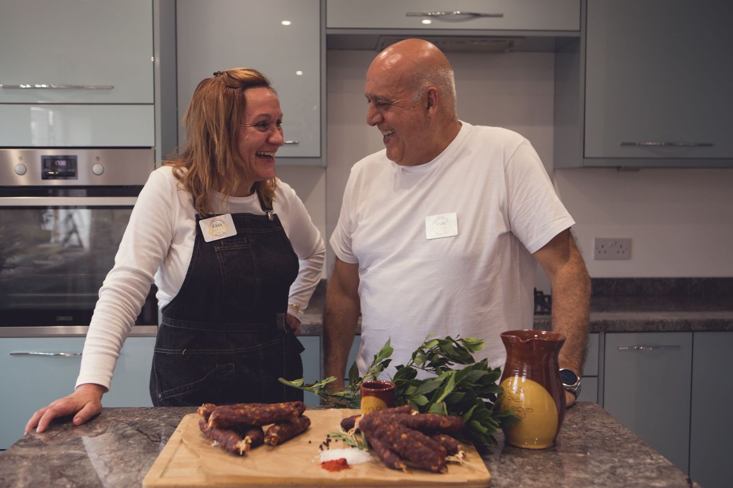 Casa Gomez, husband and wife gourmet chorizo team smiling and laughing in kitchen, commercial