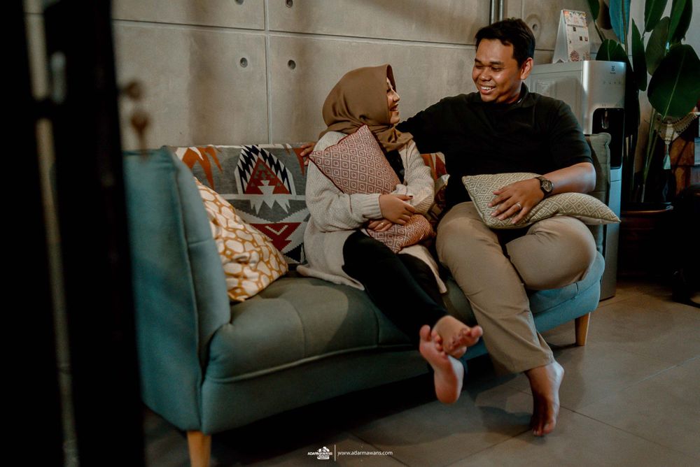 Couple sharing relaxed conversation while seated on comfortable teal couch in living room.