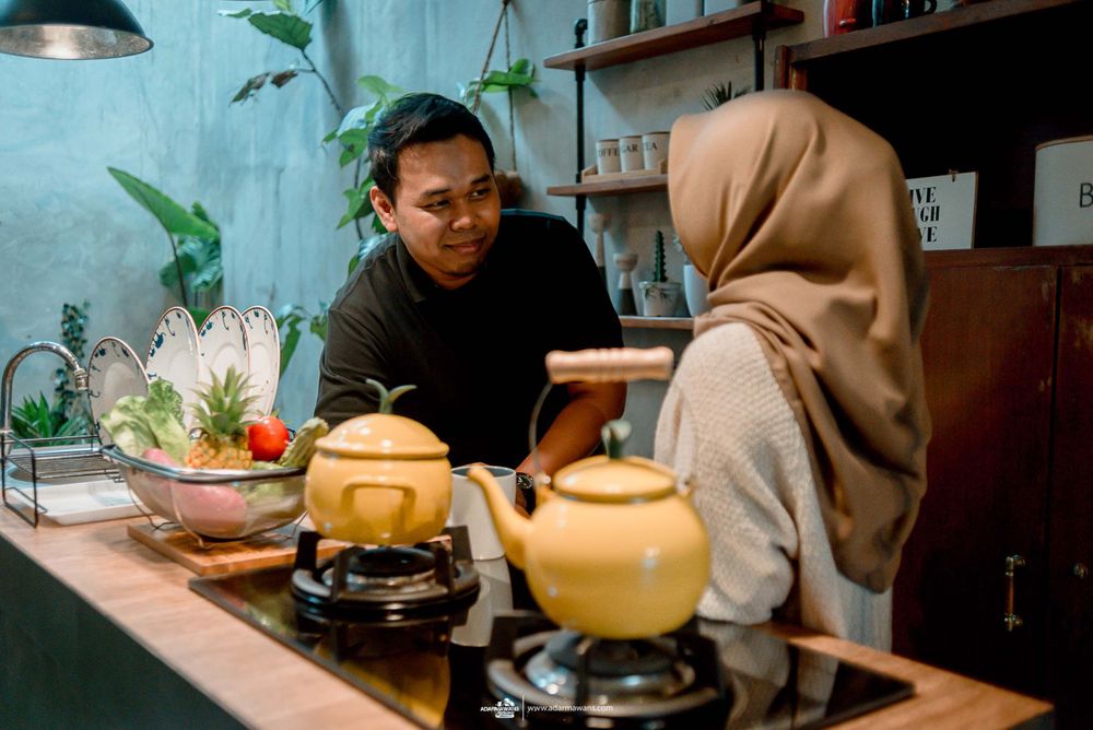 Couple preparing food together in modern kitchen with tea kettle and fresh vegetables.