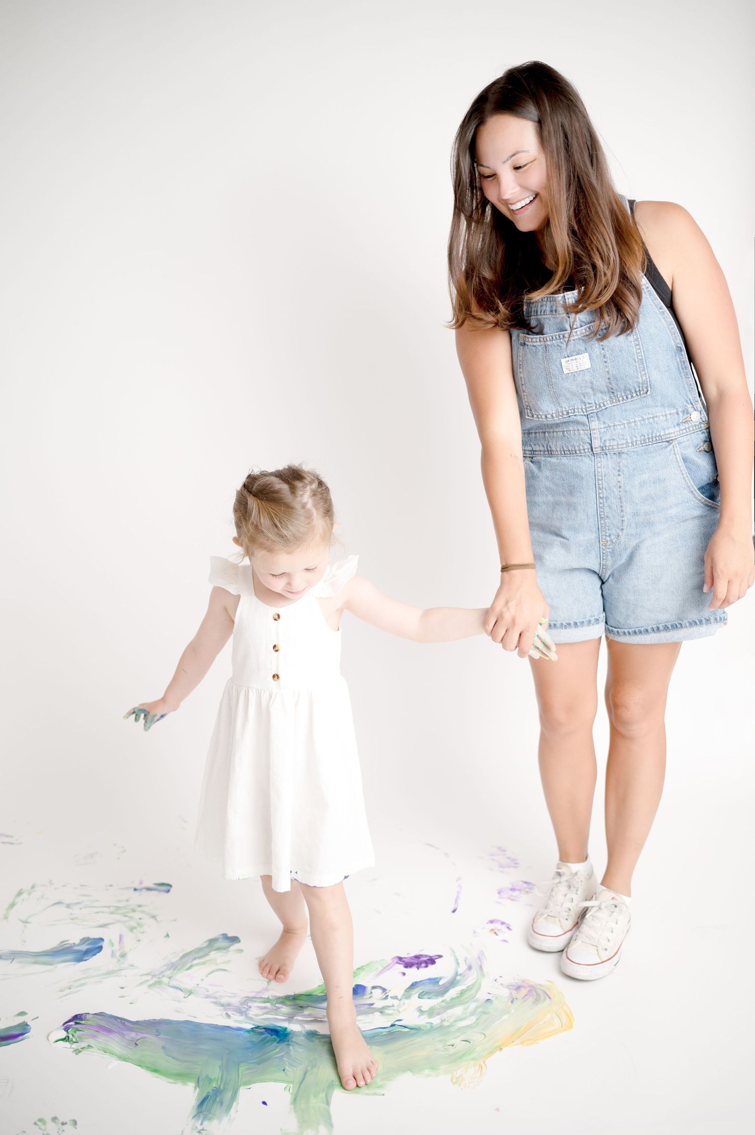 Parent and child in casual clothes creating colorful floor art together.
