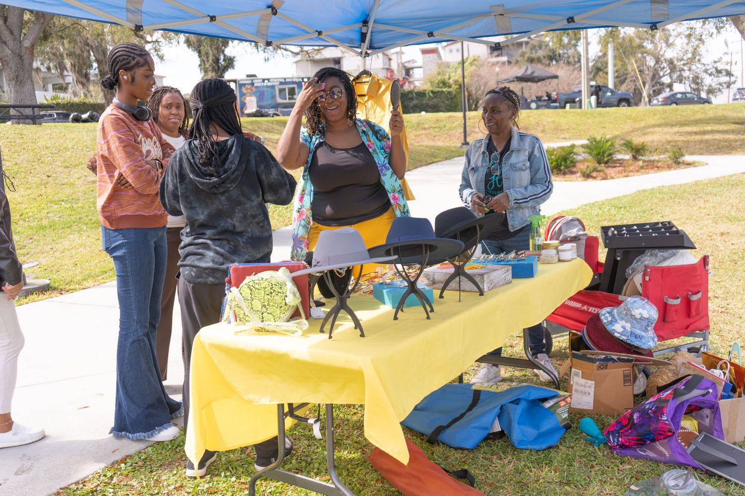 Vendors set up colorful displays at an outdoor market event with tables and merchandise.