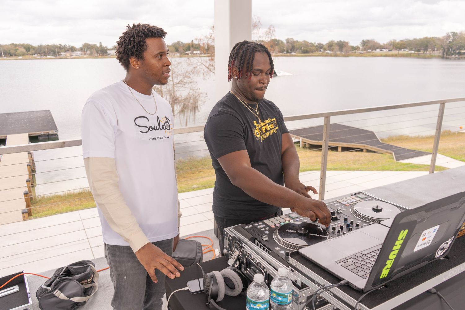 DJs work the turntables at outdoor waterfront event.