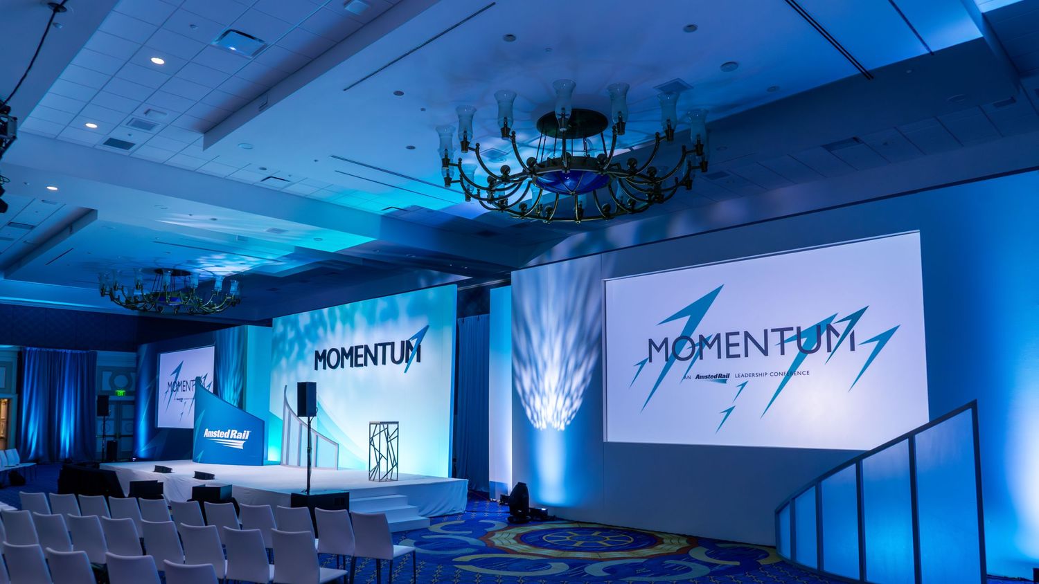 Corporate event space with blue lighting and Momentum signage displayed on screens.