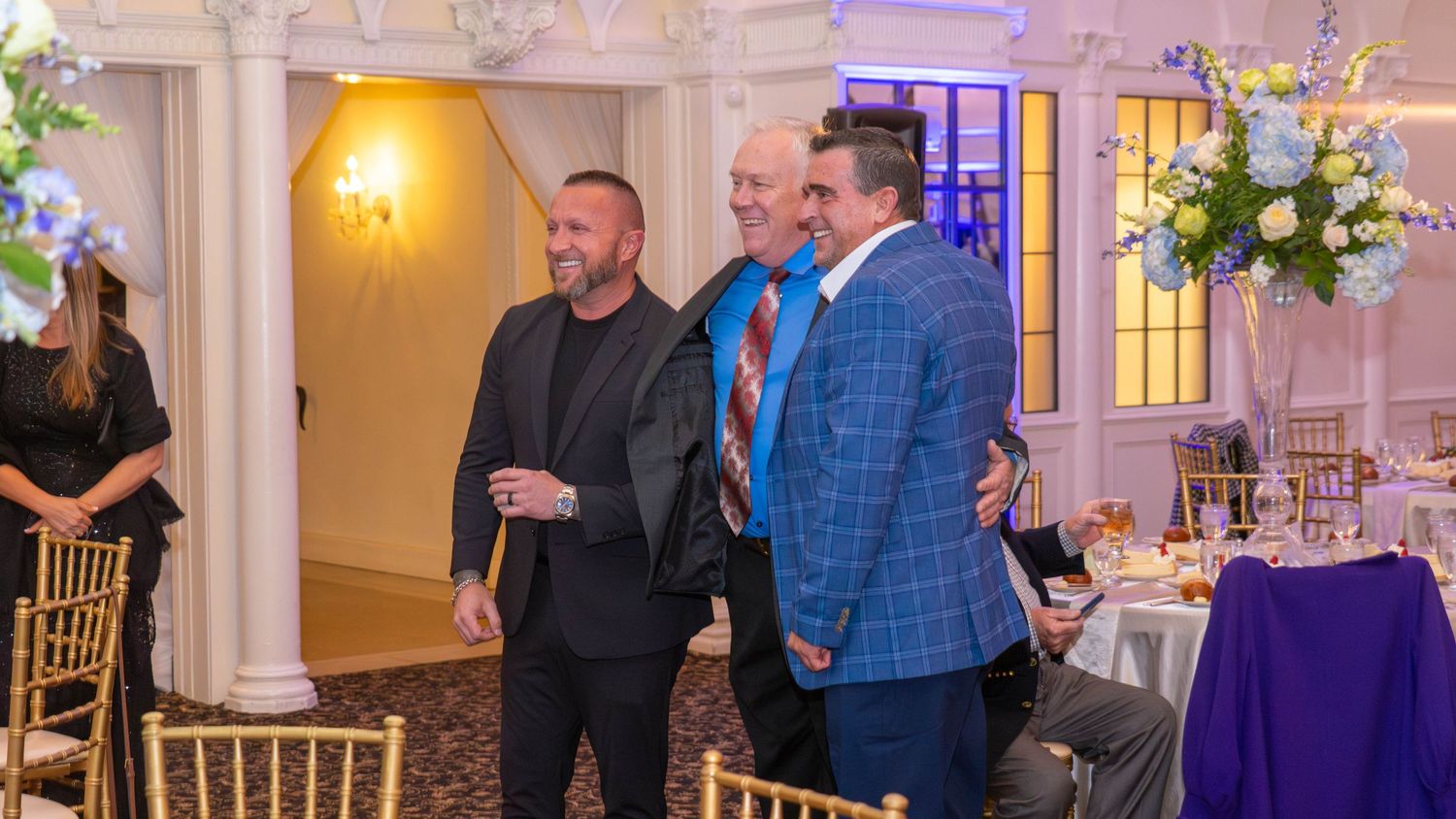 Event guests in formal attire gathered in an elegant ballroom setting.