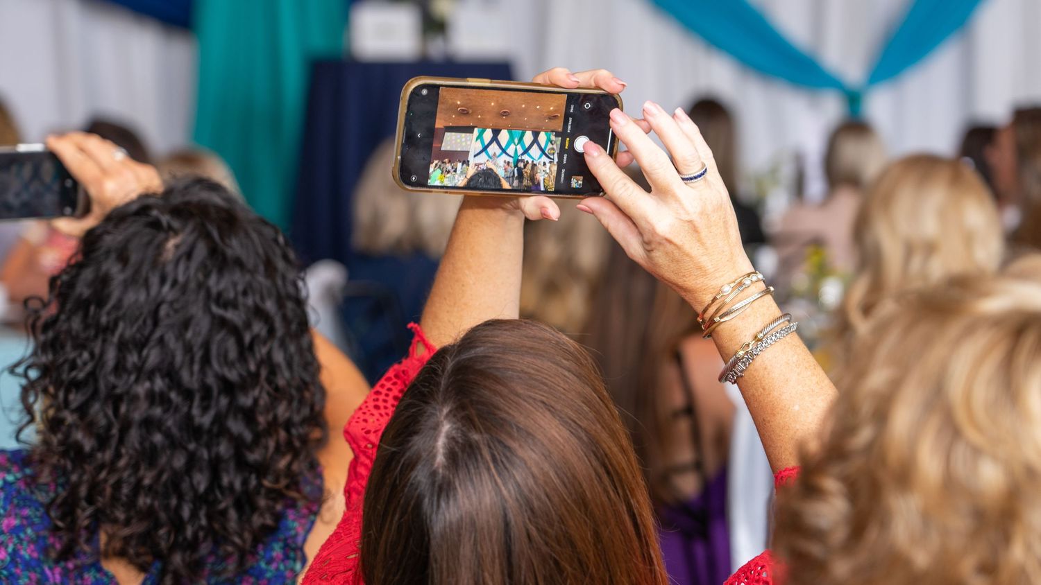Attendee capturing a moment on their smartphone during an event.