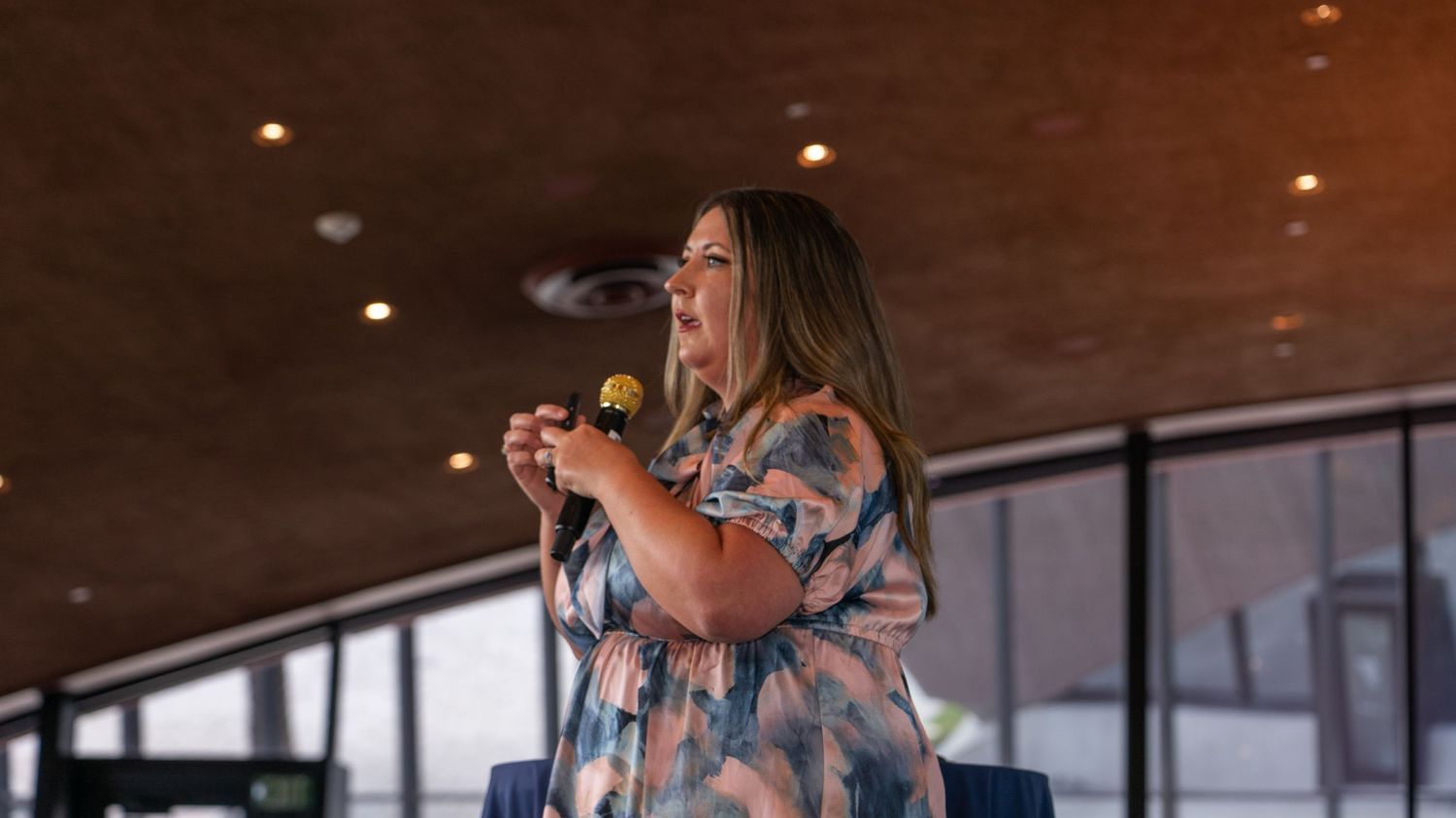 Speaker presenting on stage at an indoor conference or event venue.