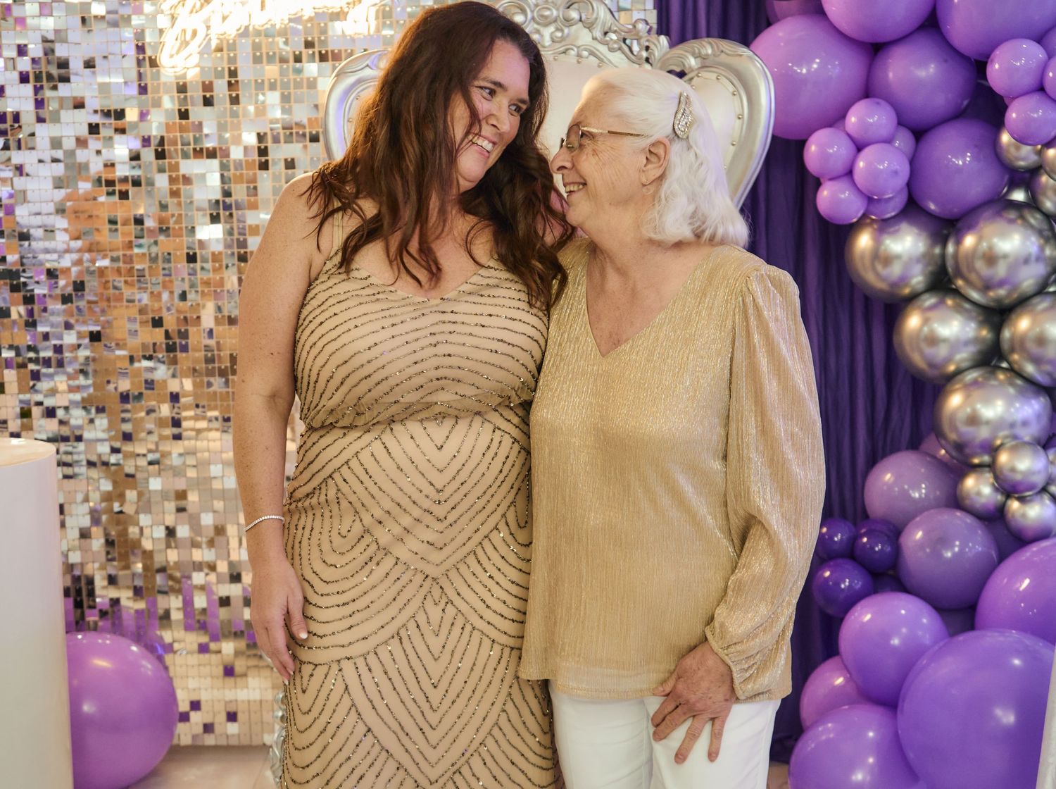 Formal event with decorative purple and silver balloon arch against a shimmering backdrop.