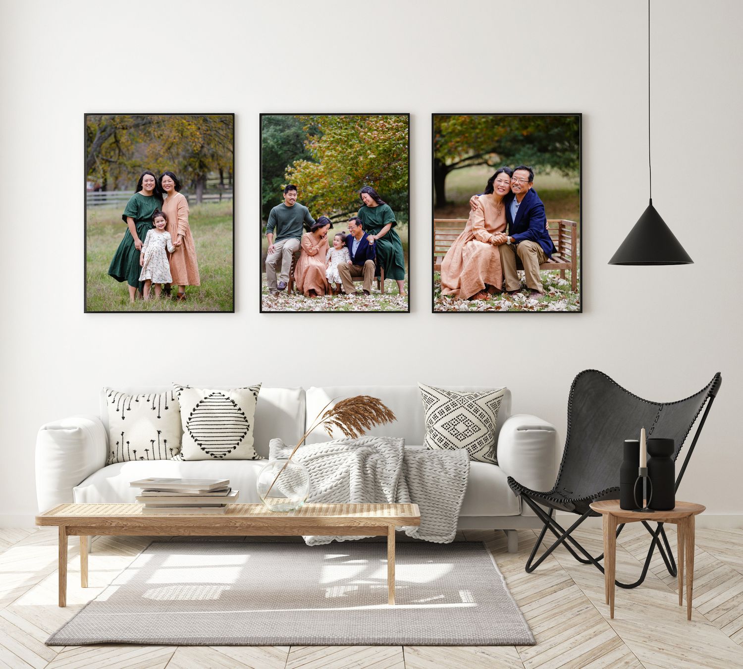 Modern living room wall displaying three family portrait canvas prints with a black pendant lamp.