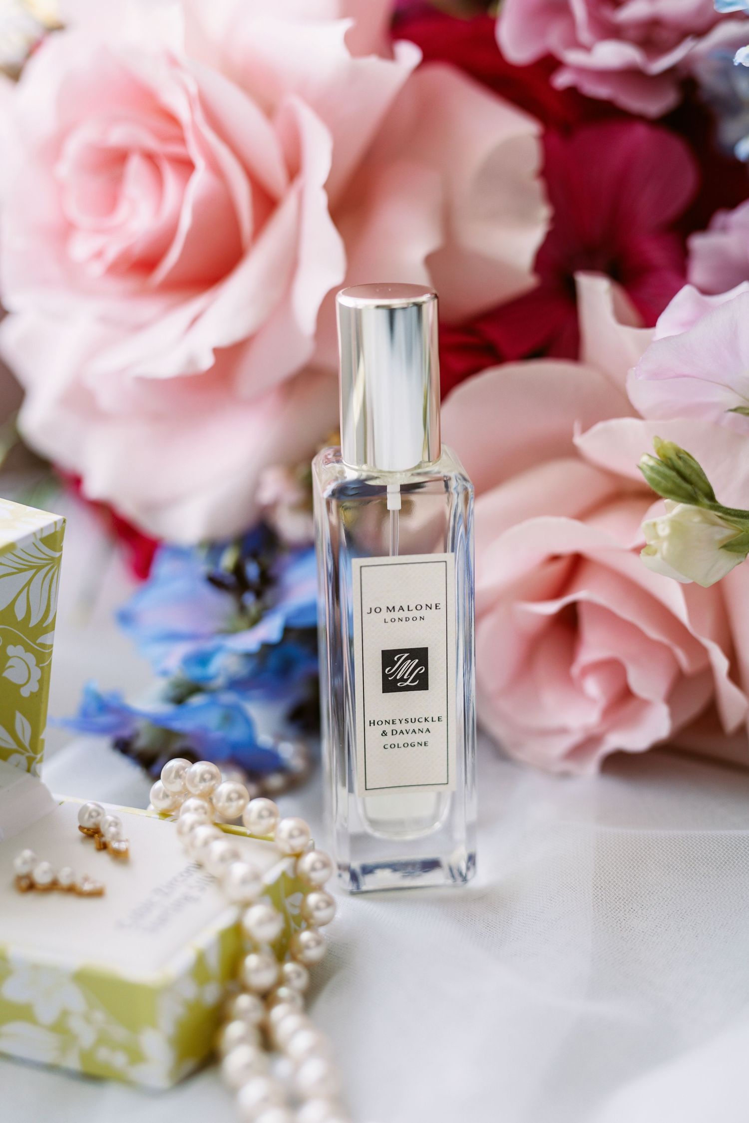 Brides details in flat lay showing perfume jewellery bouquet pretty pinks and blues