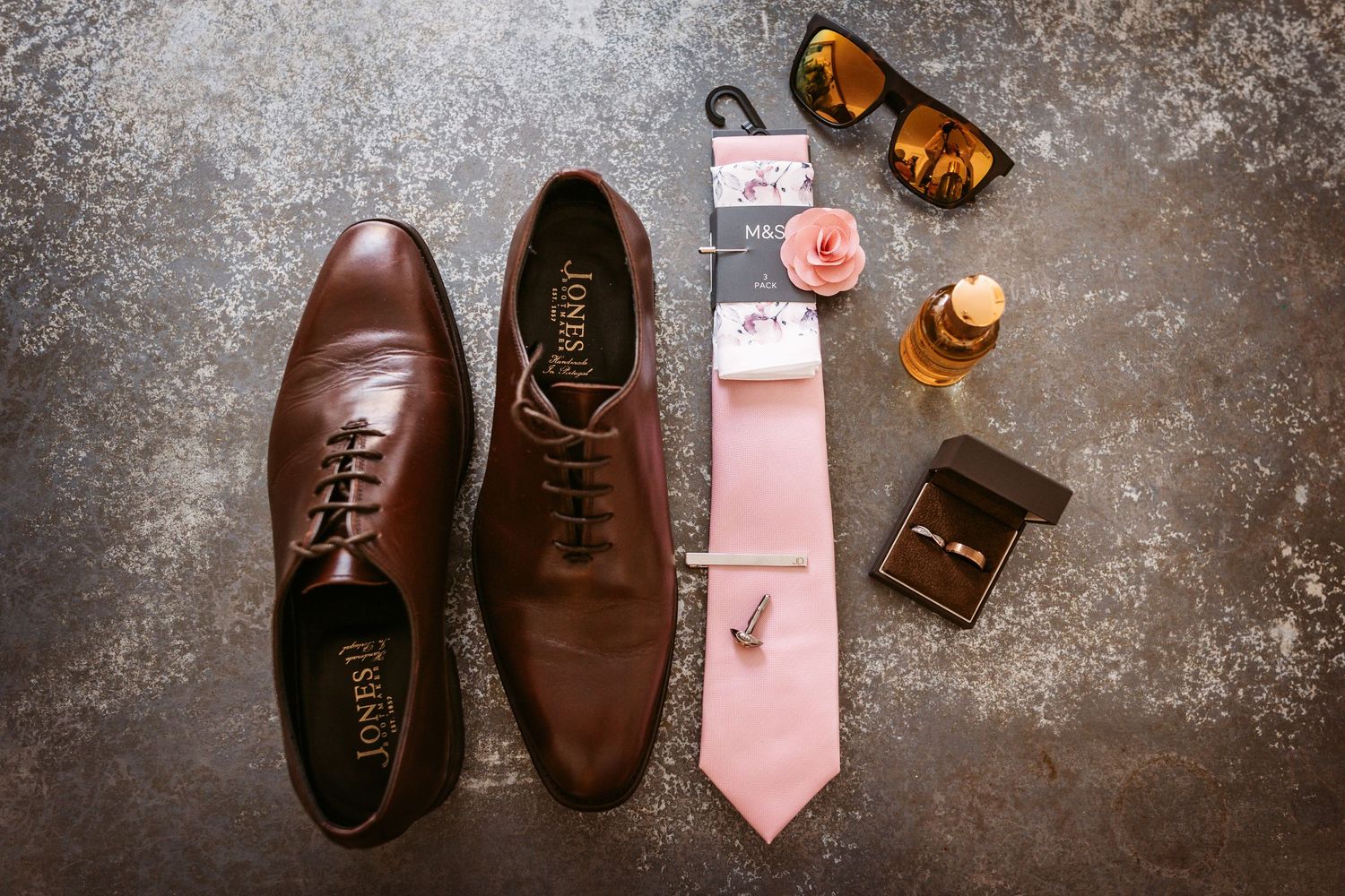 Grooms details in flat lay showing shoes tie aftershave shades and cufflinks