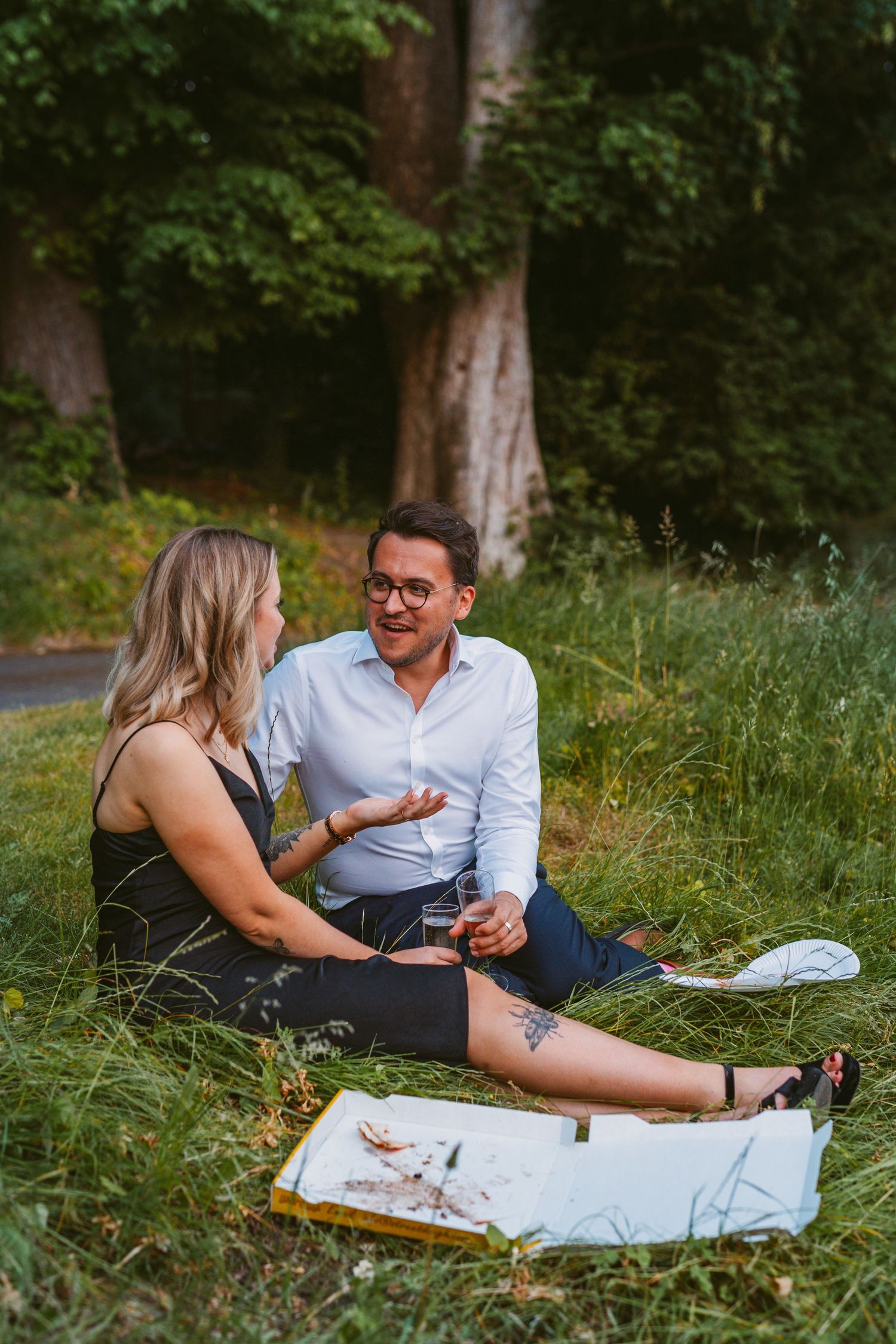 Happy couple guests sitting on grassy bank staying cool at Remenham Court wedding venue