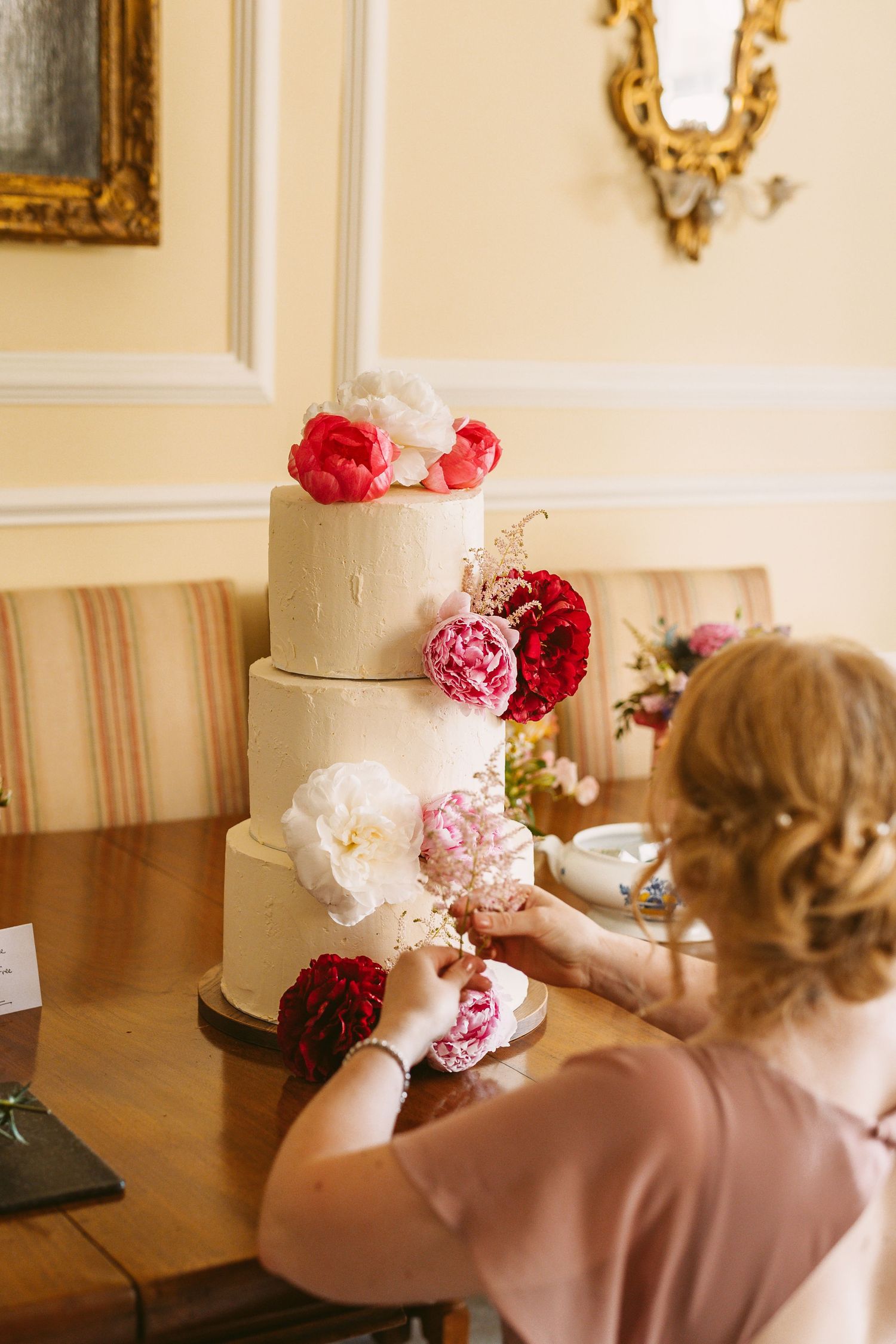 Brides sister and bridesmaid putting finishing touches to impressive homemadewedding cake