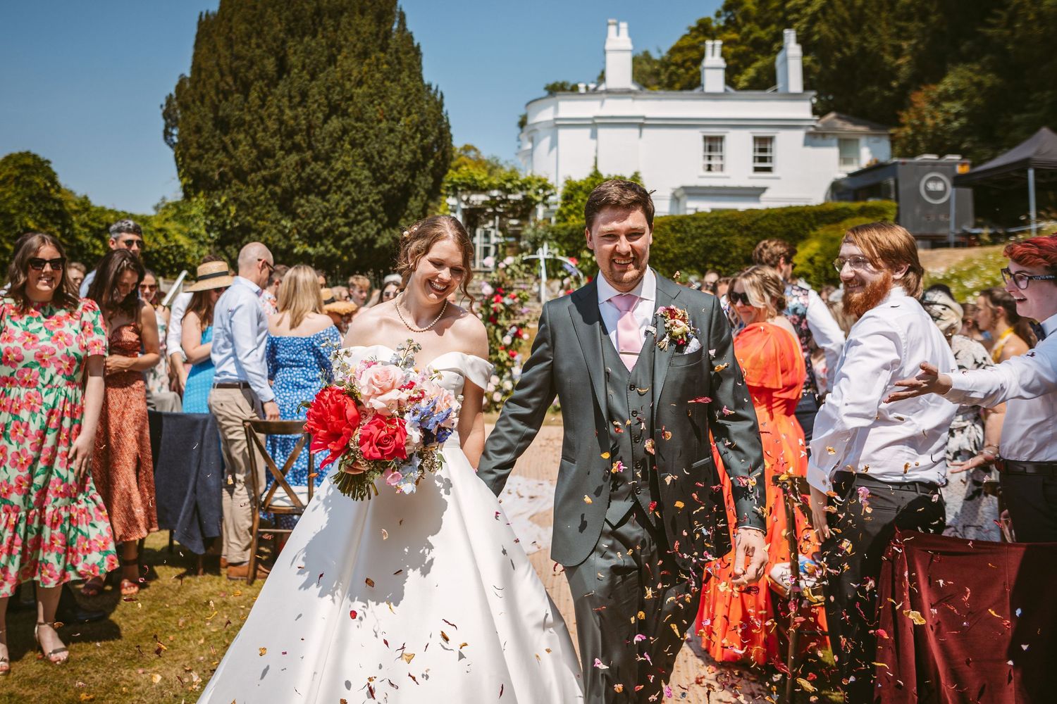 Confetti moment at Incredible wedding venue Remenham Court on hot summers day with blue sky above white house