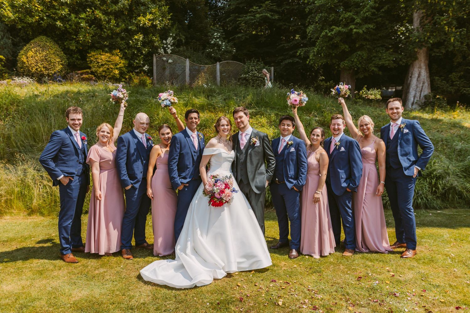 Fun bridal party bridesmaids waving bouquets in air and grooms men looking cool